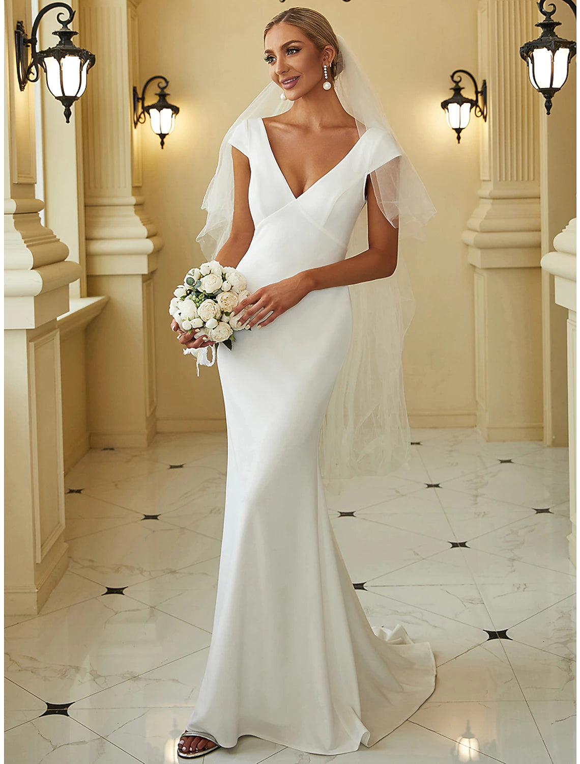 Simple white mermaid wedding dress with V-neckline, cap sleeves, and draping