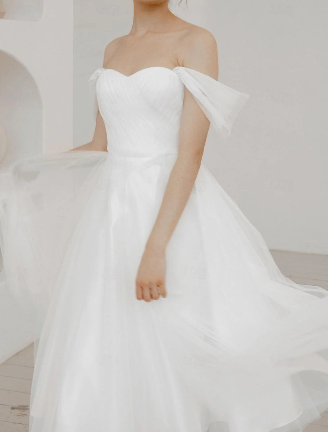 Tea-length white A-line dress in chiffon with ruched off-the-shoulder detailing