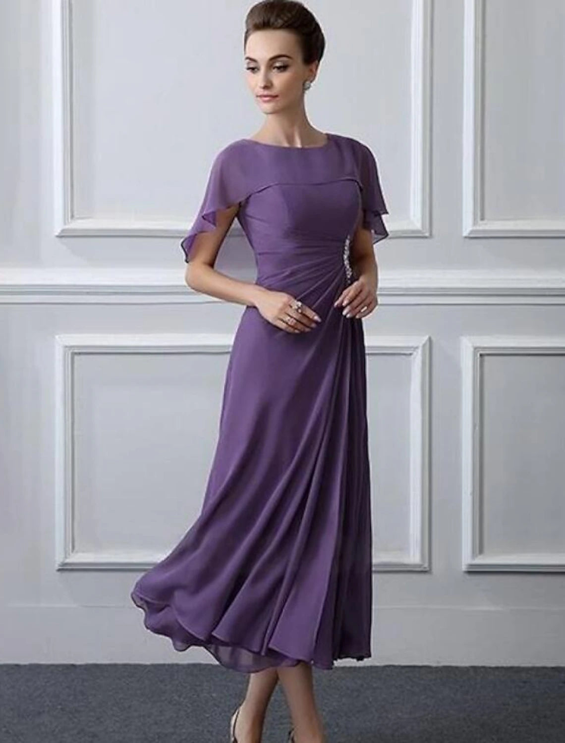 Front view of tea-length chiffon A-line mother of the bride dress with bateau neck and crystal brooch