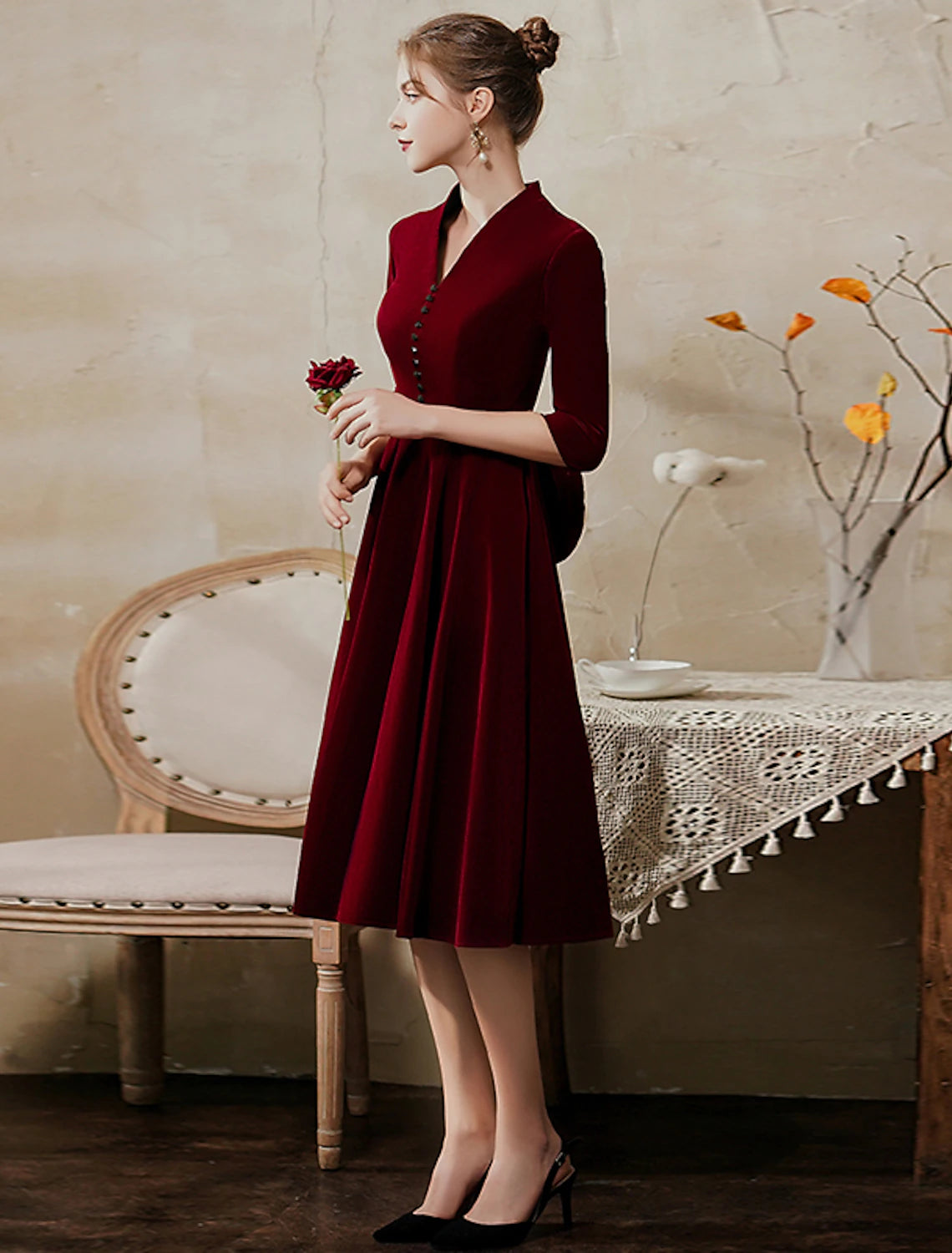 Detail view of V-neck neckline on velvet tea-length wedding guest dress