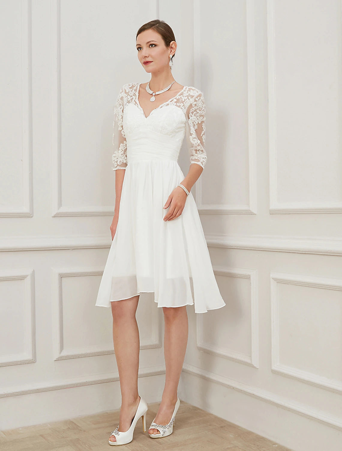 Front view of Ivory A-line knee-length chiffon wedding dress with V-neck, half sleeves, draping, and appliques