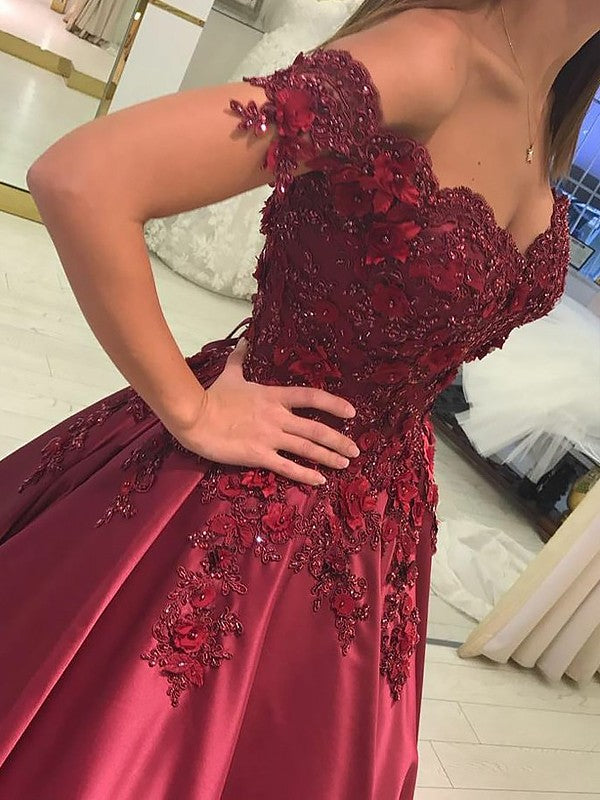 Front view of sleeveless off-the-shoulder satin ball gown dress with applique accents