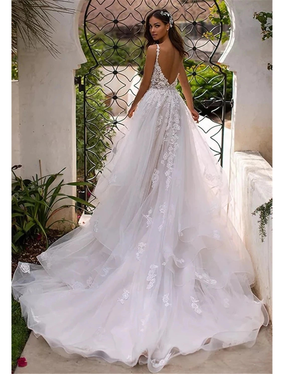 Rear view of ivory A-line bridal dress displaying open back and chapel train