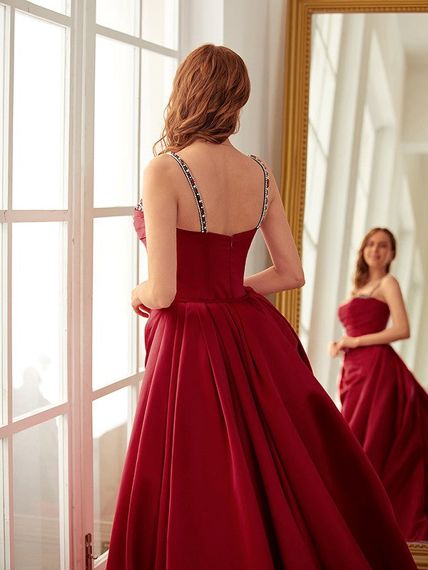 Satin sheath prom dress featuring ruched details, spaghetti straps, and chapel train