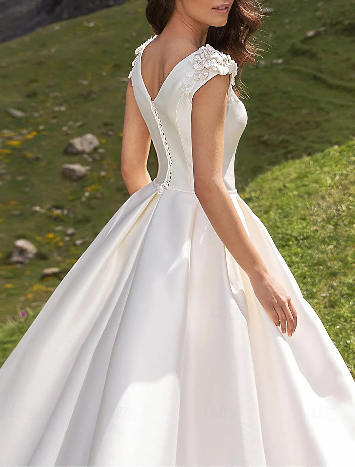 White satin bridal dress featuring a full ball gown skirt and chapel train