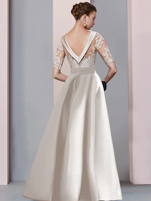 Detail view of A-line satin and lace mother of the bride dress featuring lace appliques and bow accents