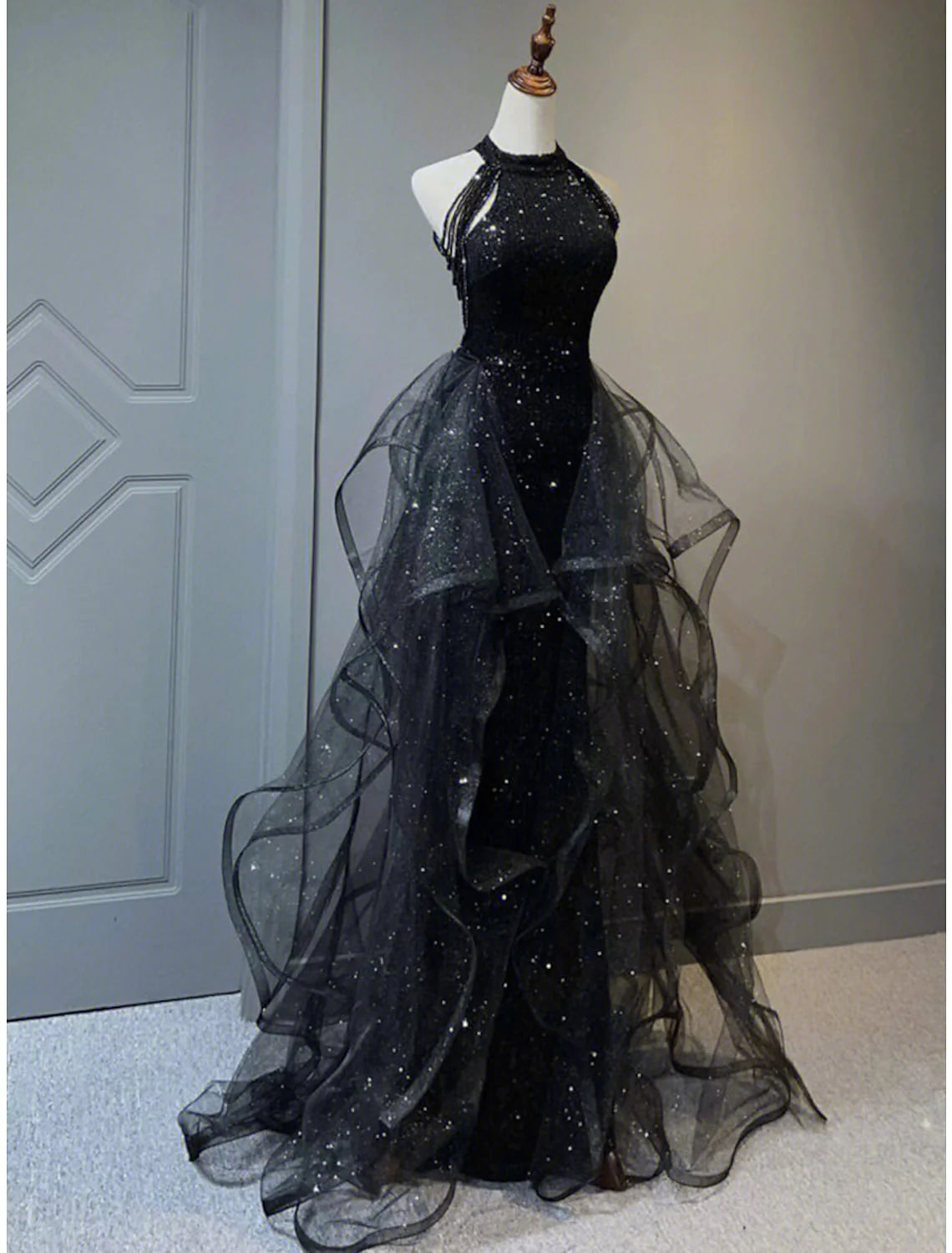 Front view of sleeveless halter neck A-line sequined prom dress with sweep train in Black