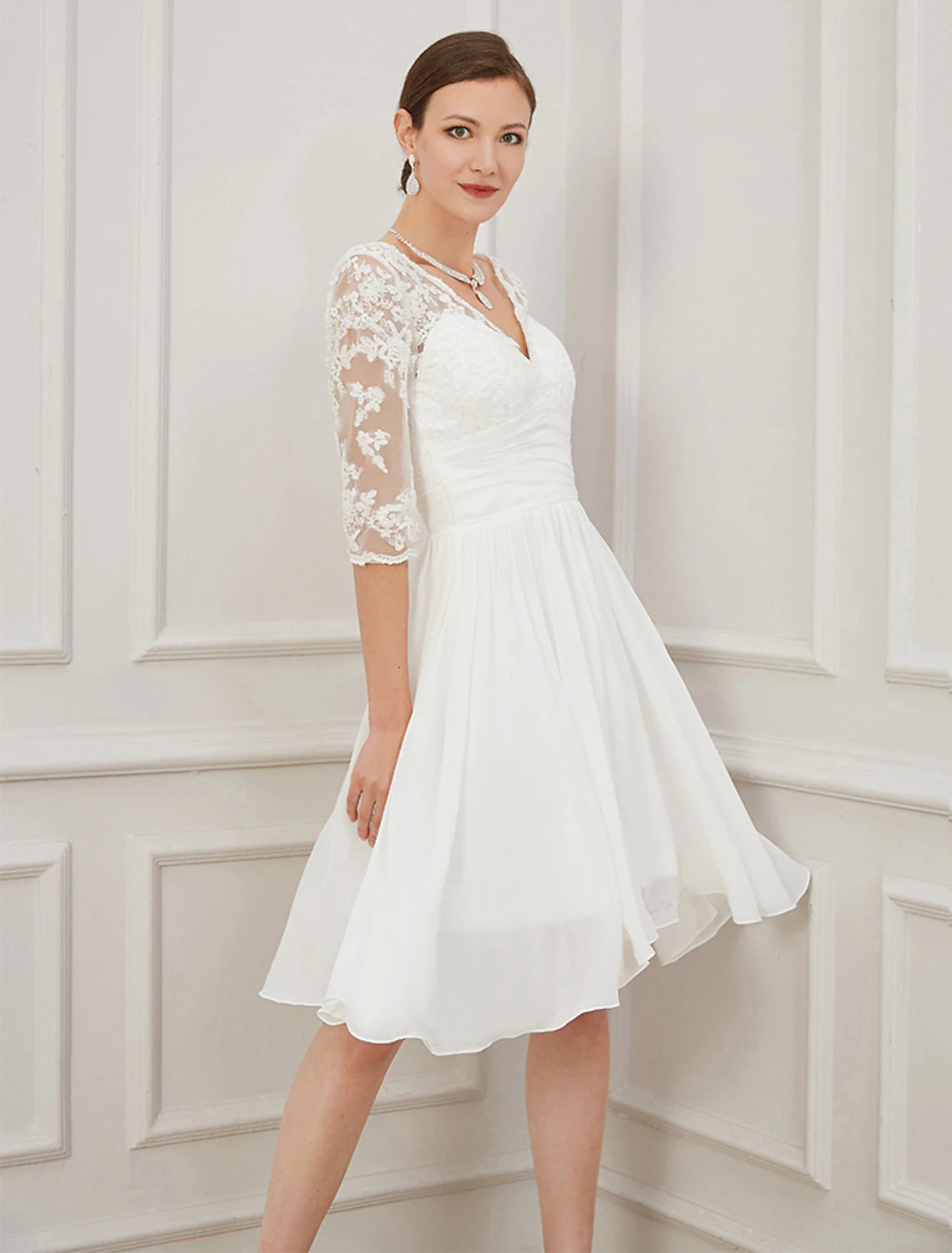 Detailed view of Ivory knee-length chiffon bridal gown featuring V-neckline and applique detailing